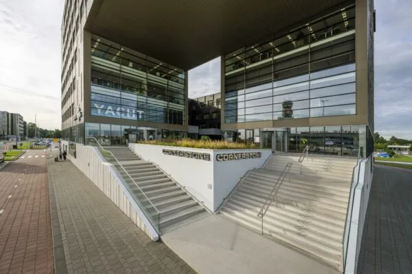 Hoofdentree van het moderne Cornerstone kantoorgebouw aan het Airportplein in Rotterdam, met brede trappen en glazen gevels.